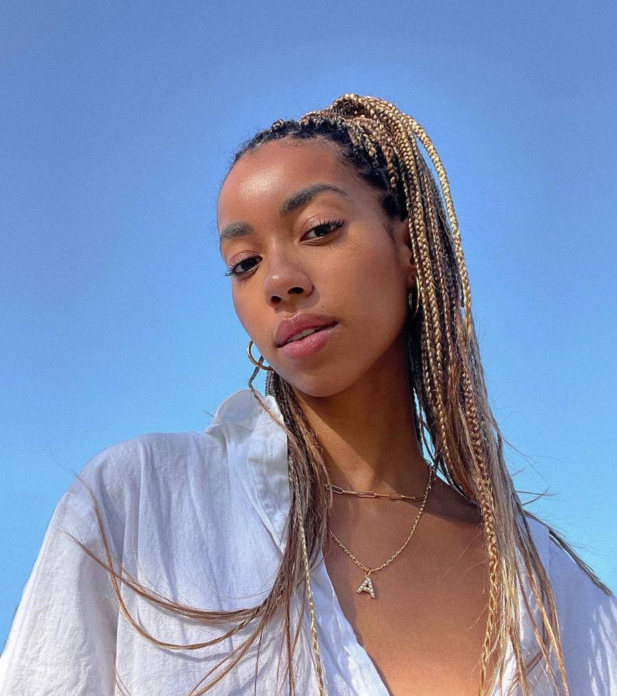 woman with long blonde braids and a blue sky behind her