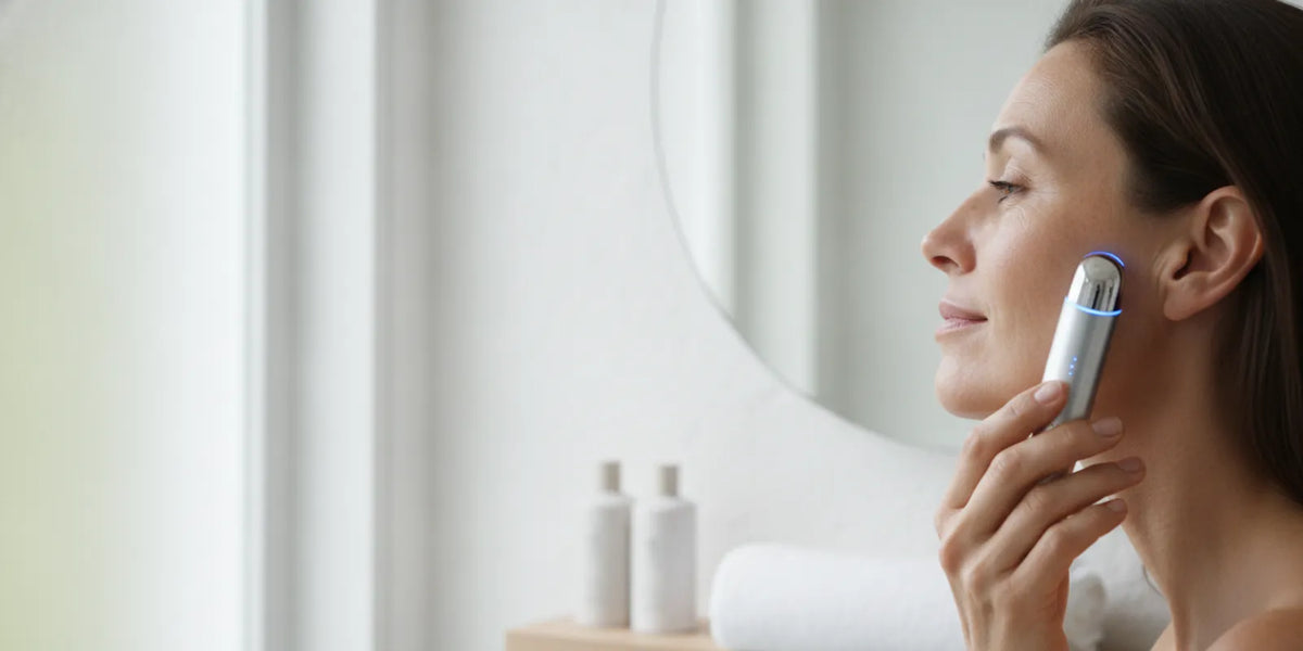 At-home skincare routine with a facial wand beside a clean towel and skincare products