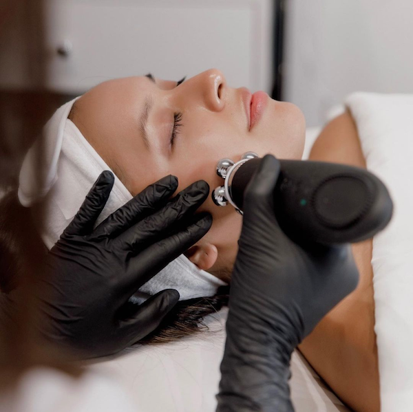 an aesthetician using two facify beauty wands on a client receiving a facial in a treatment room setting