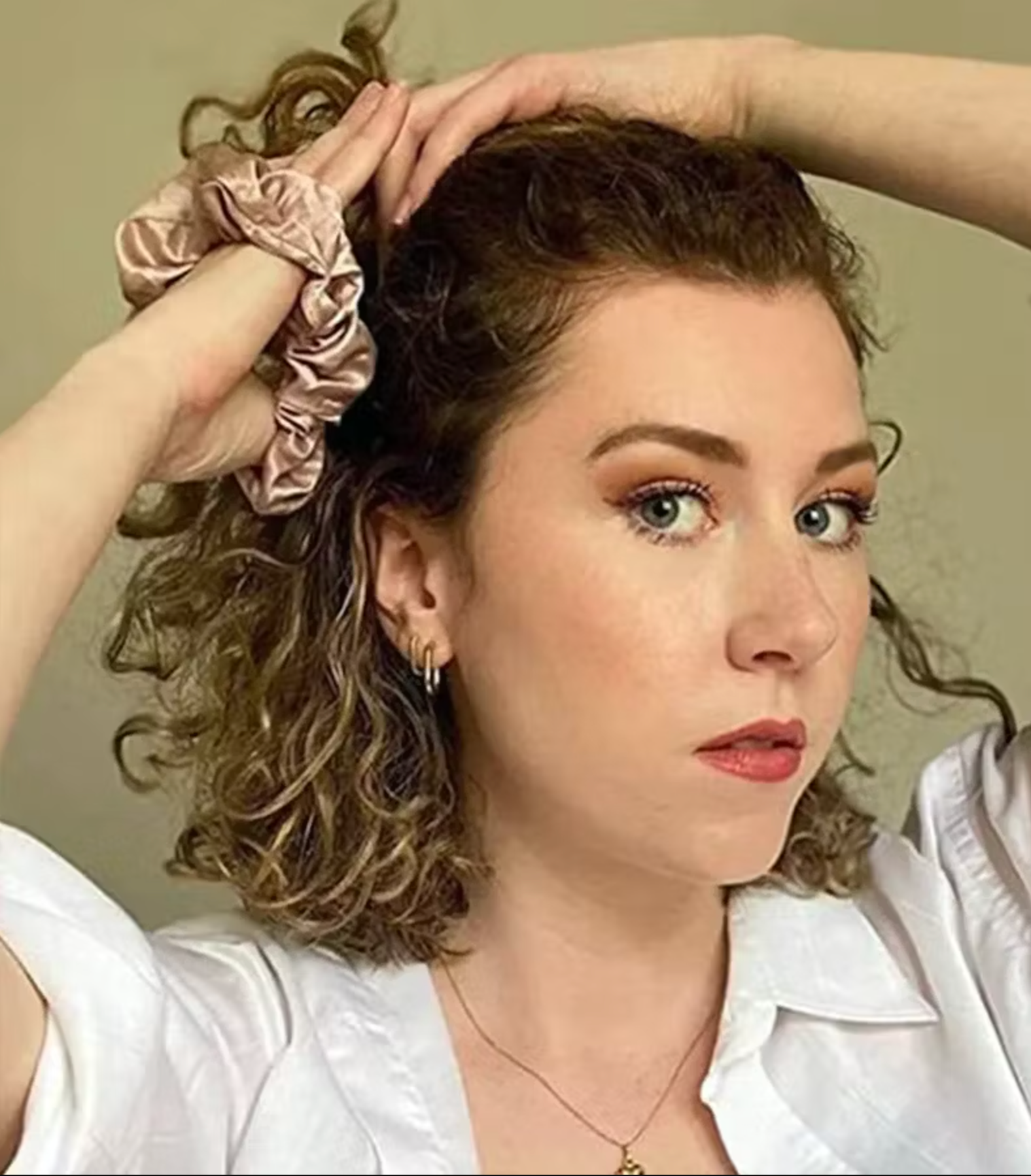 woman with curly hair putting her hair up using a silk scrunchie 